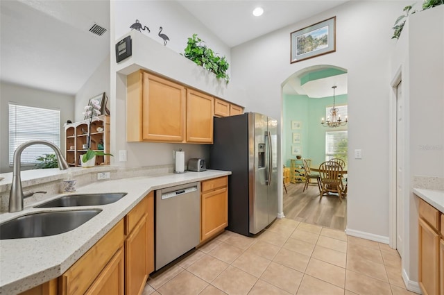 kitchen with appliances with stainless steel finishes, pendant lighting, sink, light tile patterned floors, and an inviting chandelier