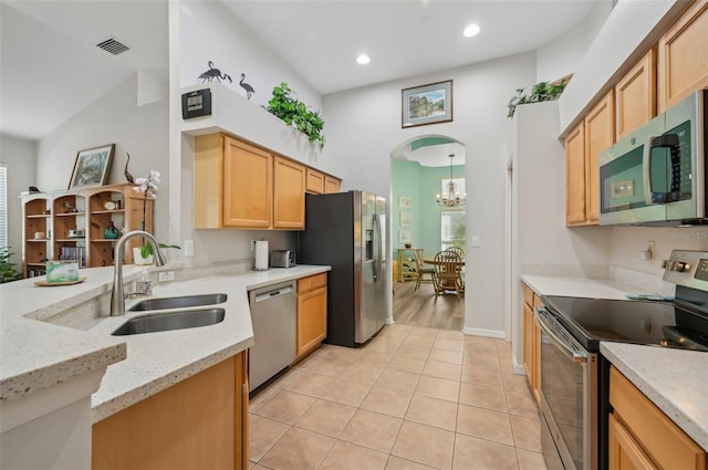 kitchen featuring sink, hanging light fixtures, light tile patterned floors, light stone counters, and stainless steel appliances