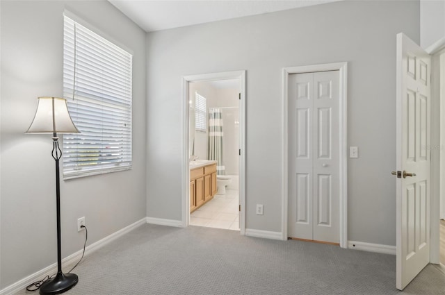 unfurnished bedroom with ensuite bathroom, light colored carpet, and a closet