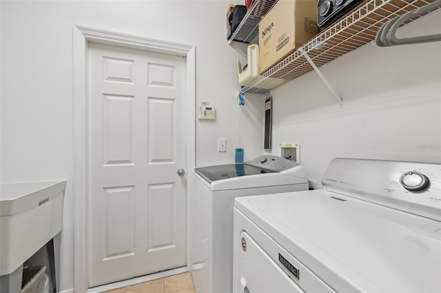 laundry room featuring sink, washing machine and clothes dryer, and light tile patterned flooring