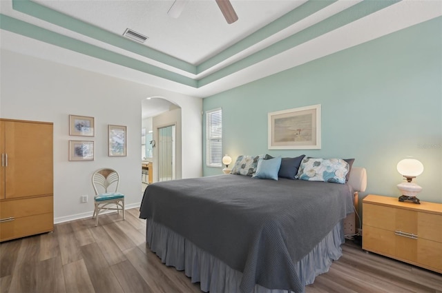 bedroom featuring hardwood / wood-style flooring, a raised ceiling, and ceiling fan