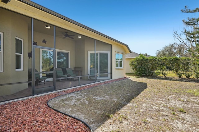 rear view of property with ceiling fan and a patio area