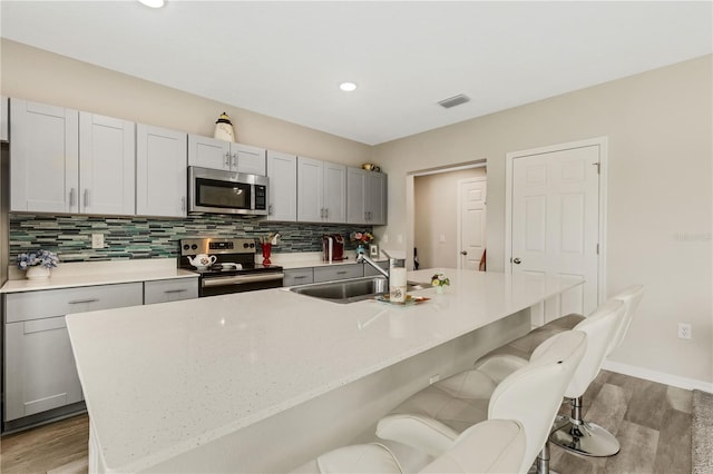 kitchen with appliances with stainless steel finishes, a kitchen island with sink, sink, and a breakfast bar