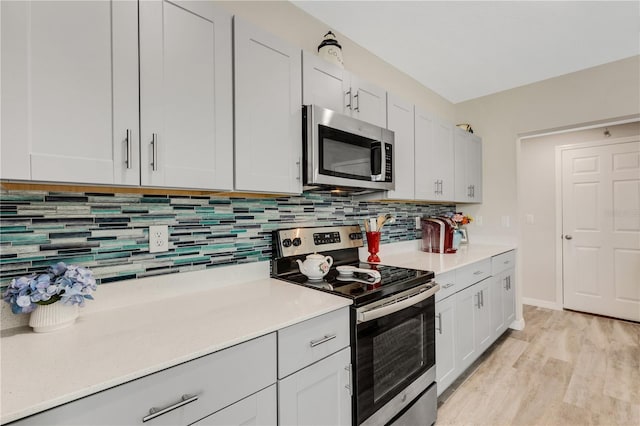 kitchen with white cabinetry, decorative backsplash, stainless steel appliances, and light wood-type flooring