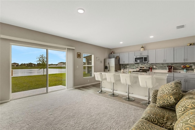 kitchen featuring a kitchen island with sink, stainless steel appliances, a kitchen breakfast bar, and a water view