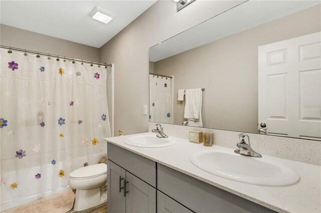 full bathroom featuring shower / bath combo, vanity, and toilet