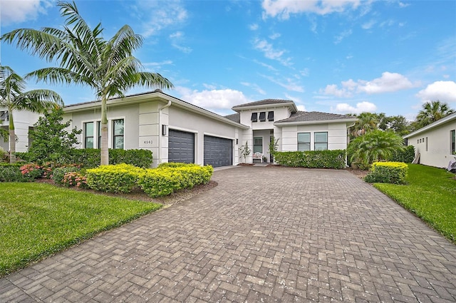 view of front of property featuring an attached garage, a front yard, decorative driveway, and stucco siding