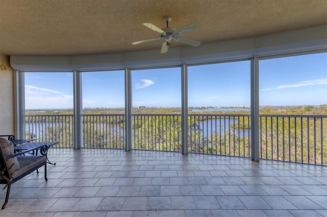 sunroom / solarium with a water view and ceiling fan