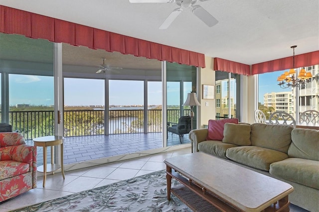 tiled living room with ceiling fan with notable chandelier and a water view