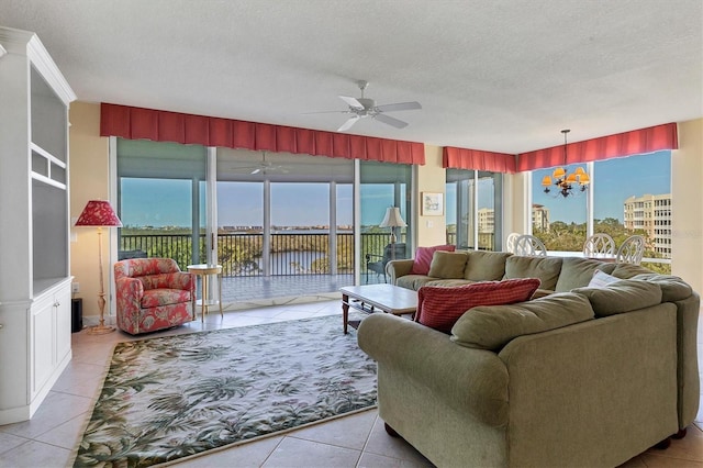 tiled living room with a water view, a textured ceiling, and a wealth of natural light