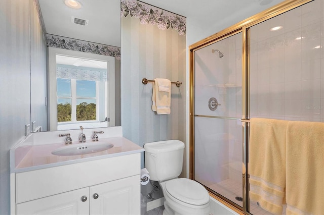 bathroom with a shower with door, vanity, and toilet