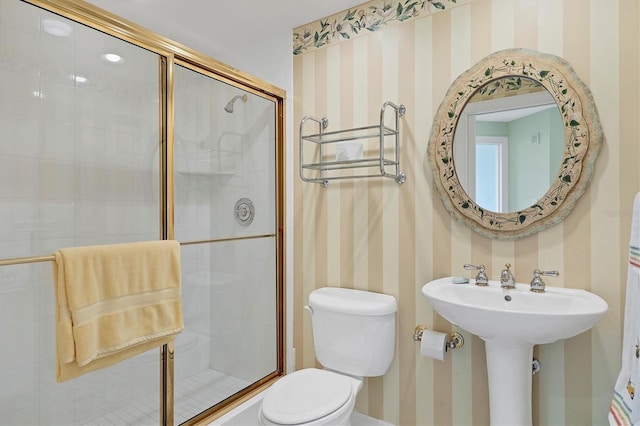 bathroom with sink, a shower with shower door, and toilet