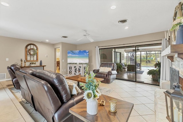 living room featuring light tile patterned floors, a premium fireplace, and ceiling fan