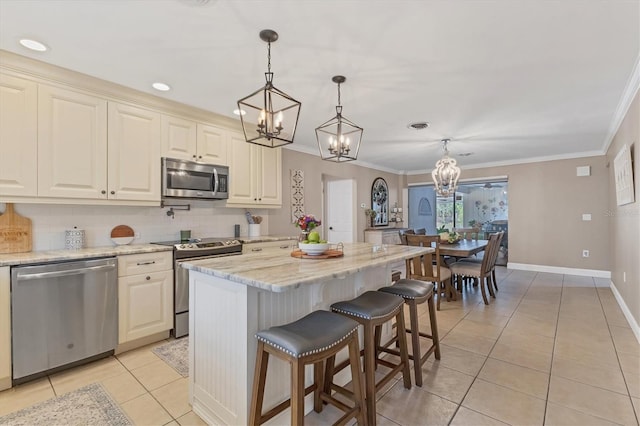 kitchen with hanging light fixtures, a kitchen island, light stone countertops, and appliances with stainless steel finishes