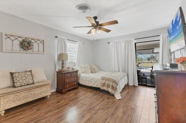 bedroom featuring ceiling fan, a textured ceiling, access to exterior, and dark hardwood / wood-style flooring