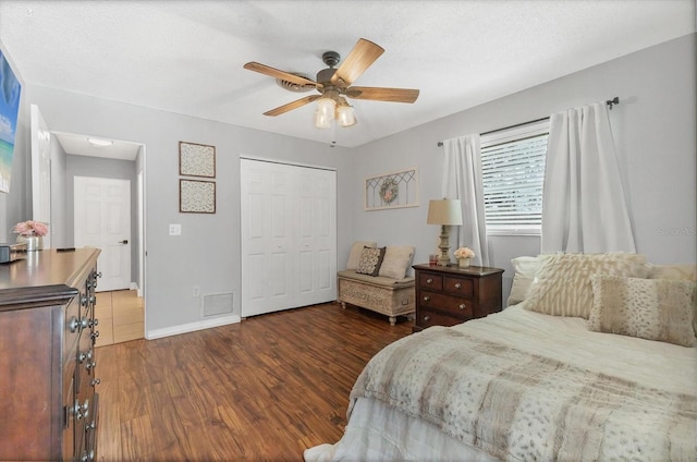 bedroom with a closet, a textured ceiling, dark hardwood / wood-style floors, and ceiling fan