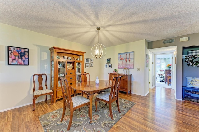 dining space featuring hardwood / wood-style floors, a chandelier, and a textured ceiling