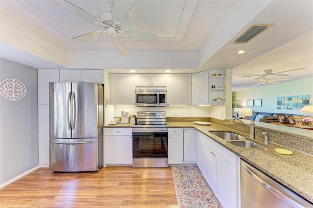 kitchen with sink, white cabinetry, light stone counters, appliances with stainless steel finishes, and light hardwood / wood-style floors