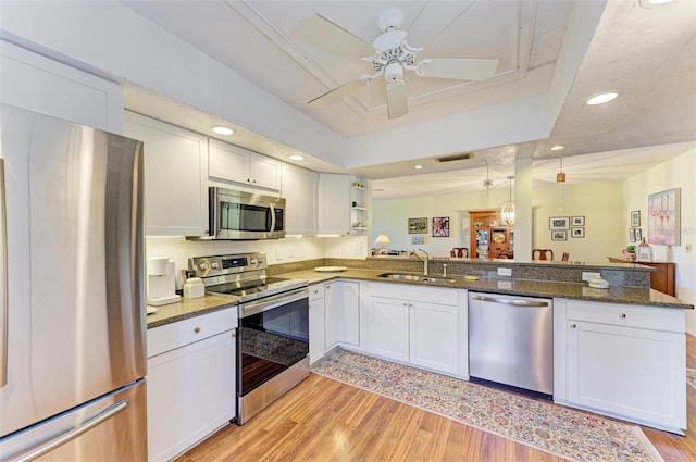 kitchen featuring white cabinetry, sink, kitchen peninsula, stainless steel appliances, and light wood-type flooring