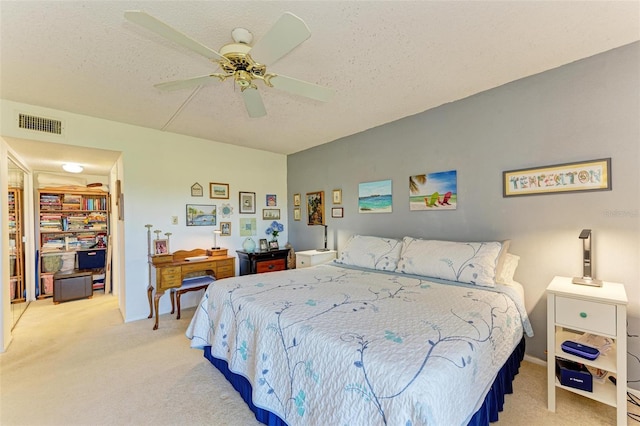 bedroom with ceiling fan, light carpet, and a textured ceiling