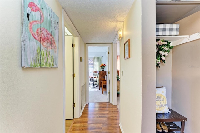 hallway featuring wood-type flooring and a textured ceiling