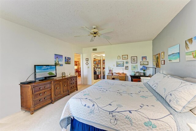 bedroom with visible vents, light carpet, a textured ceiling, and ceiling fan