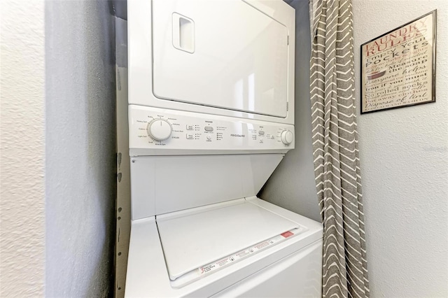 laundry area featuring laundry area, stacked washer / drying machine, and a textured wall