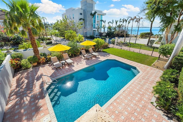 view of pool featuring a lawn, a patio, and a water view