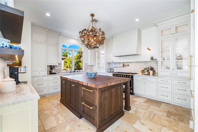 kitchen with high end stainless steel range oven, white cabinetry, a center island, wood counters, and custom exhaust hood