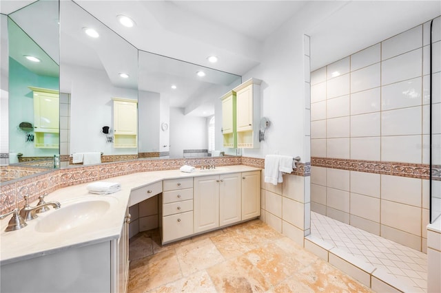 bathroom with a tile shower and vanity