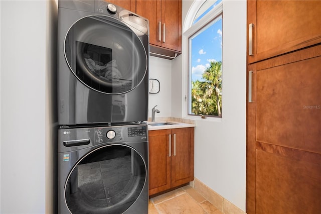 laundry room featuring cabinets, stacked washer / drying machine, and sink