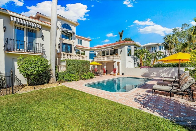 rear view of house featuring a fenced in pool, a yard, a patio area, and a balcony