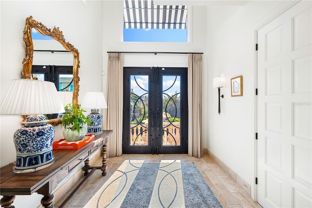 entryway with baseboards, french doors, a wealth of natural light, and stone tile floors