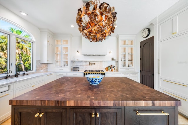 kitchen with glass insert cabinets, a center island, butcher block counters, and decorative backsplash