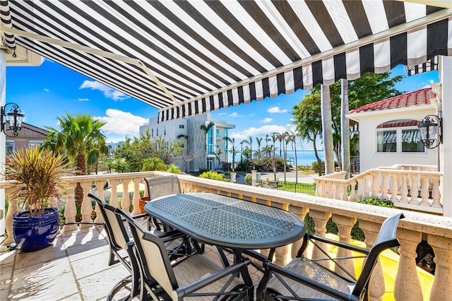 balcony featuring outdoor dining space and a water view