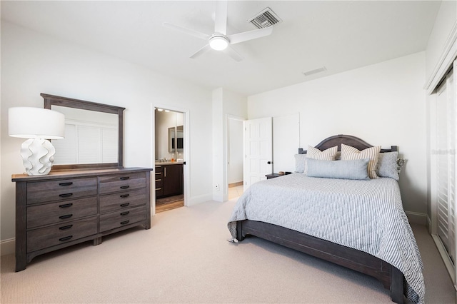 bedroom featuring ceiling fan, light colored carpet, visible vents, baseboards, and ensuite bath