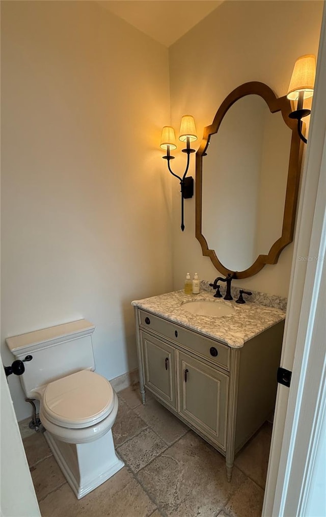 half bath with vanity, toilet, and baseboards