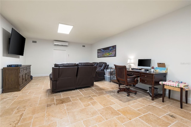 office space featuring a wall unit AC, stone finish flooring, visible vents, and baseboards