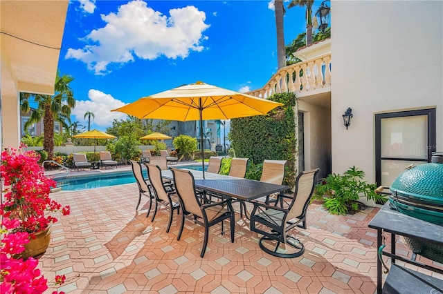 view of patio with a balcony, a fenced in pool, and outdoor dining space