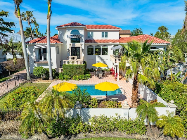 back of house featuring a fenced in pool, a patio, a fenced backyard, a tile roof, and stucco siding