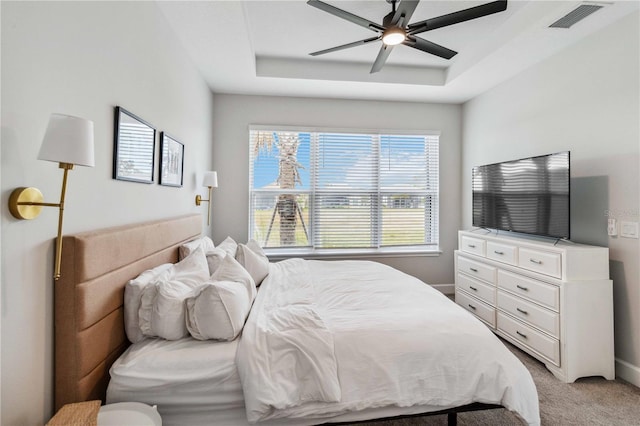 carpeted bedroom featuring ceiling fan and a tray ceiling