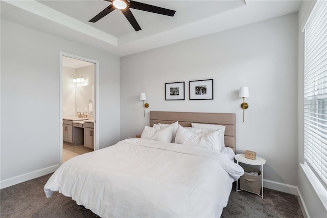 bedroom featuring ceiling fan, ensuite bath, a raised ceiling, and light carpet