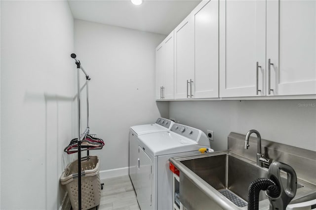 washroom with cabinets, light hardwood / wood-style floors, sink, and washing machine and clothes dryer