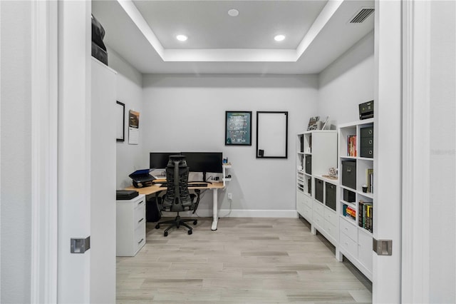 office featuring a tray ceiling and light wood-type flooring