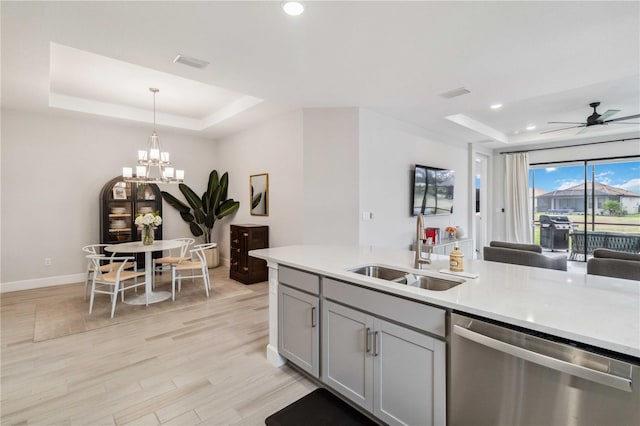 kitchen featuring pendant lighting, sink, stainless steel dishwasher, and a raised ceiling