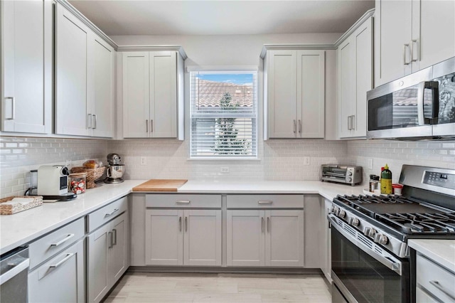 kitchen with stainless steel appliances, gray cabinets, and decorative backsplash