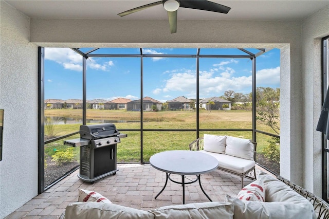 sunroom / solarium with a water view and ceiling fan