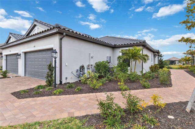 3016 Formia Ct, Bradenton, FL 34211 - view of side of home featuring stucco siding, an attached garage, decorative driveway, and a tiled roof