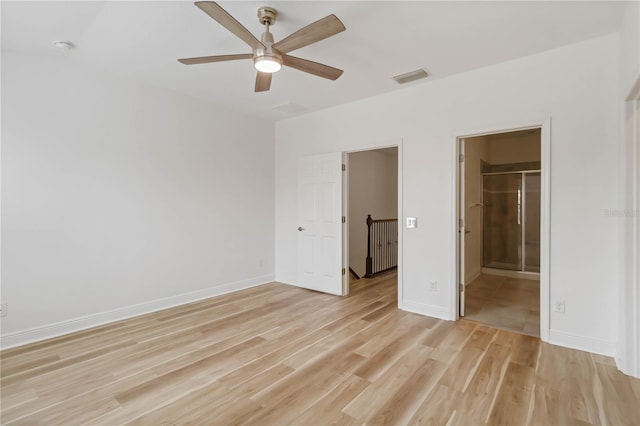 unfurnished bedroom featuring ceiling fan, ensuite bathroom, light hardwood / wood-style floors, a walk in closet, and a closet