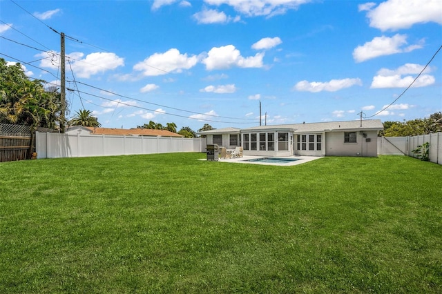 rear view of property featuring a fenced in pool, a patio, and a lawn